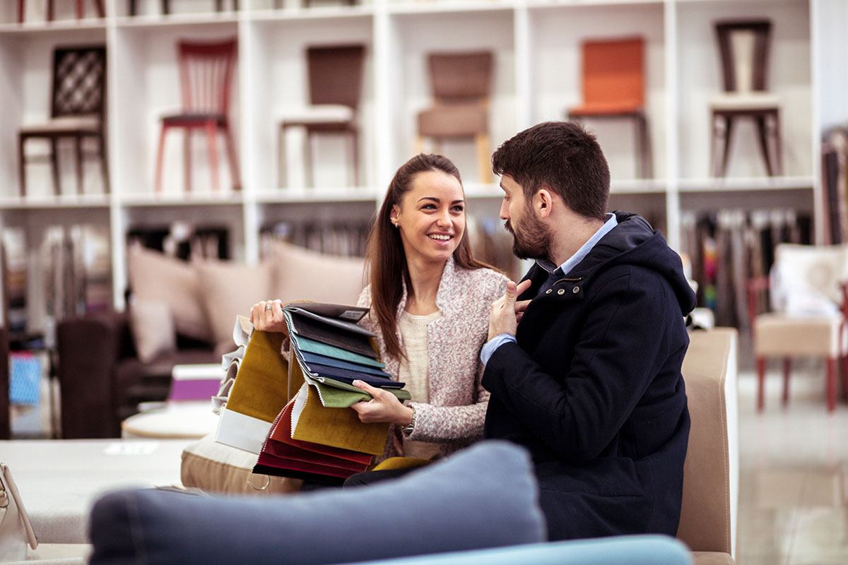 Couple debate which fabric to use on their new dining room chairs in an upscale department store. 