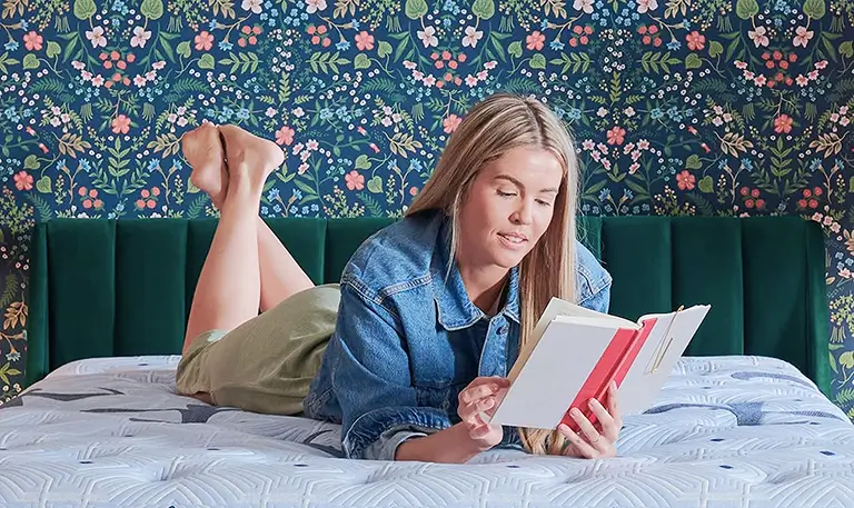 Woman reading on mattress in bedroom